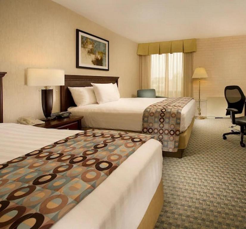 堪萨斯城Hotel Lotus Kansas City Stadium的酒店客房,配有两张床和椅子
