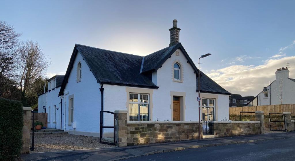 PencaitlandISLAY House,Comfortable Home with private garden, Pencaitland, East Lothian, Scotland的街上有黑屋顶的白色房子