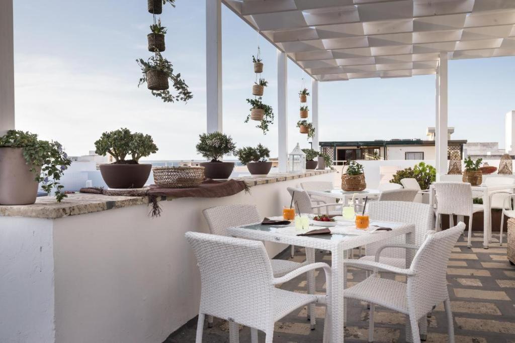 加利波利Faro Bianco Gallipoli - Suites & Apartments的庭院配有白色桌椅和盆栽植物