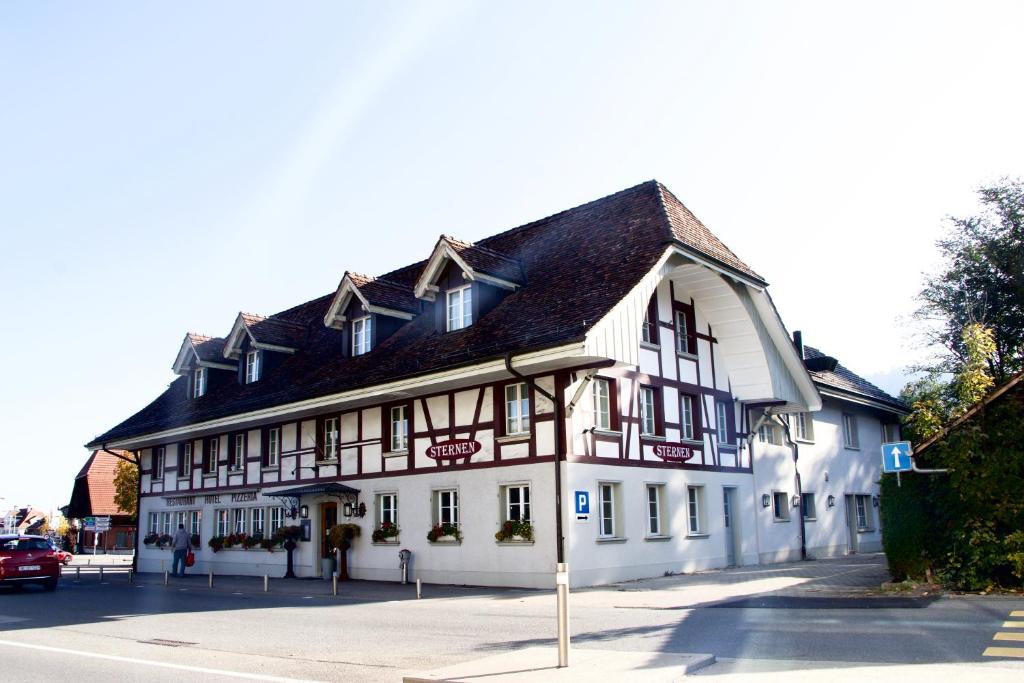 伯尔尼Hotel & Restaurant Sternen Köniz bei Bern的一条白色的街道上,有黑色屋顶