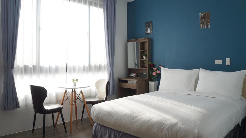 鹿港镇Lukang Holiday Hostel的一间卧室配有一张床、一张桌子和一个窗户。