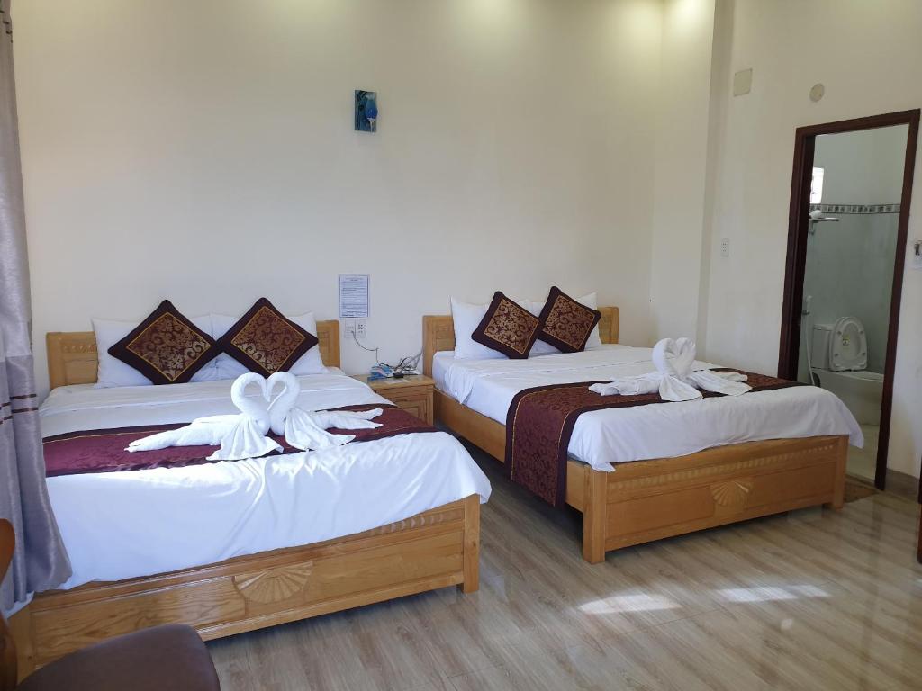 邦美蜀Kim Ngân Hotel Buôn Ma Thuột的配有白色弓的旅馆客房的两张床