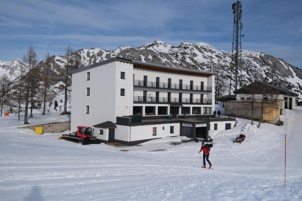 Tauplitzalm斯特勒霍夫阿尔佩恩酒店的滑雪者在建筑物前的雪中