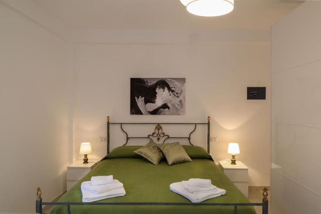 陶尔米纳La Perla的一间卧室配有绿床和2条毛巾