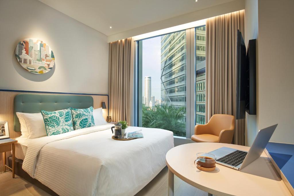 新加坡Citadines Raffles Place Singapore的配有床和笔记本电脑桌的酒店客房