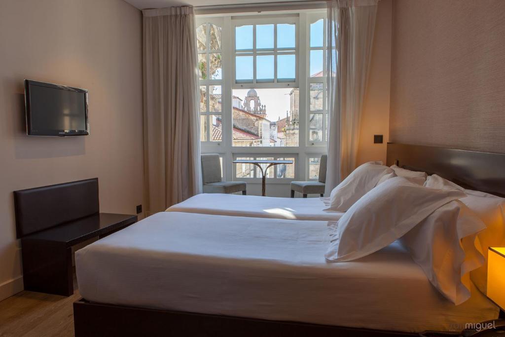 圣地亚哥－德孔波斯特拉Hotel San Miguel的酒店客房设有两张床和窗户。