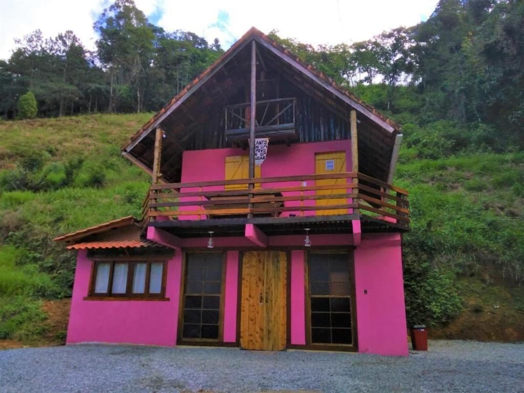 卢米亚Bangalô Boa Ventura的粉红色的房子,上面设有阳台