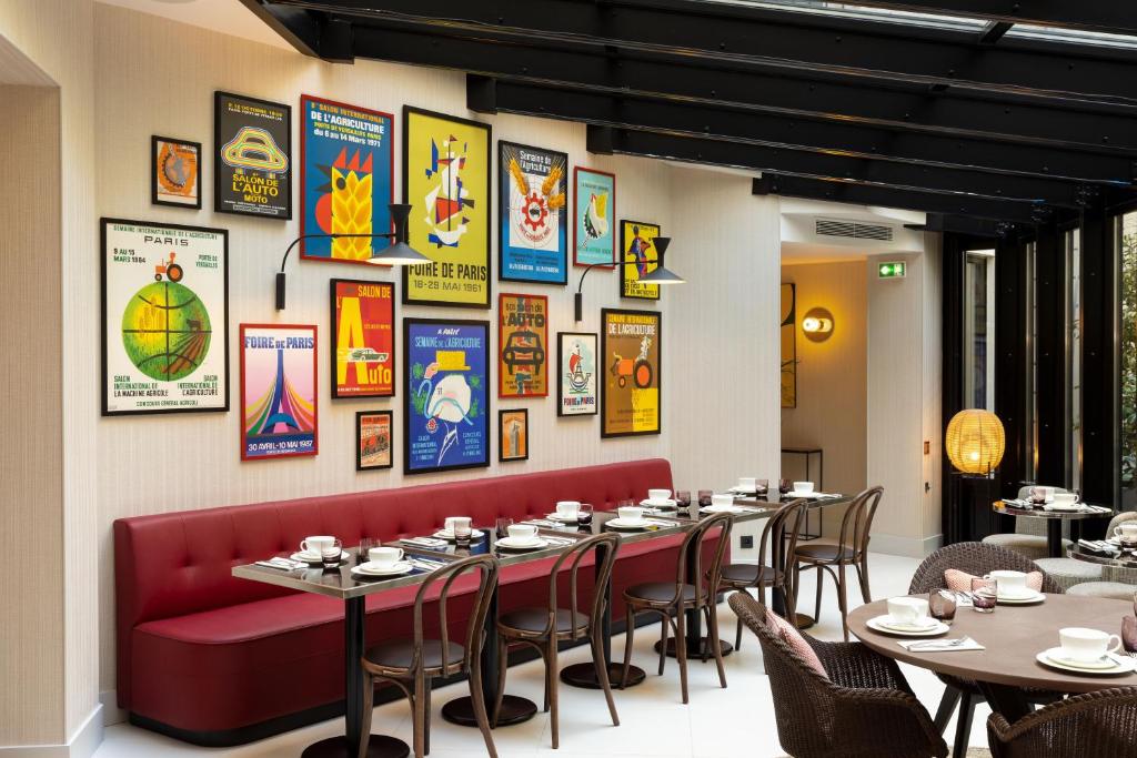巴黎Hôtel Moderniste的餐厅设有桌椅和墙上的海报