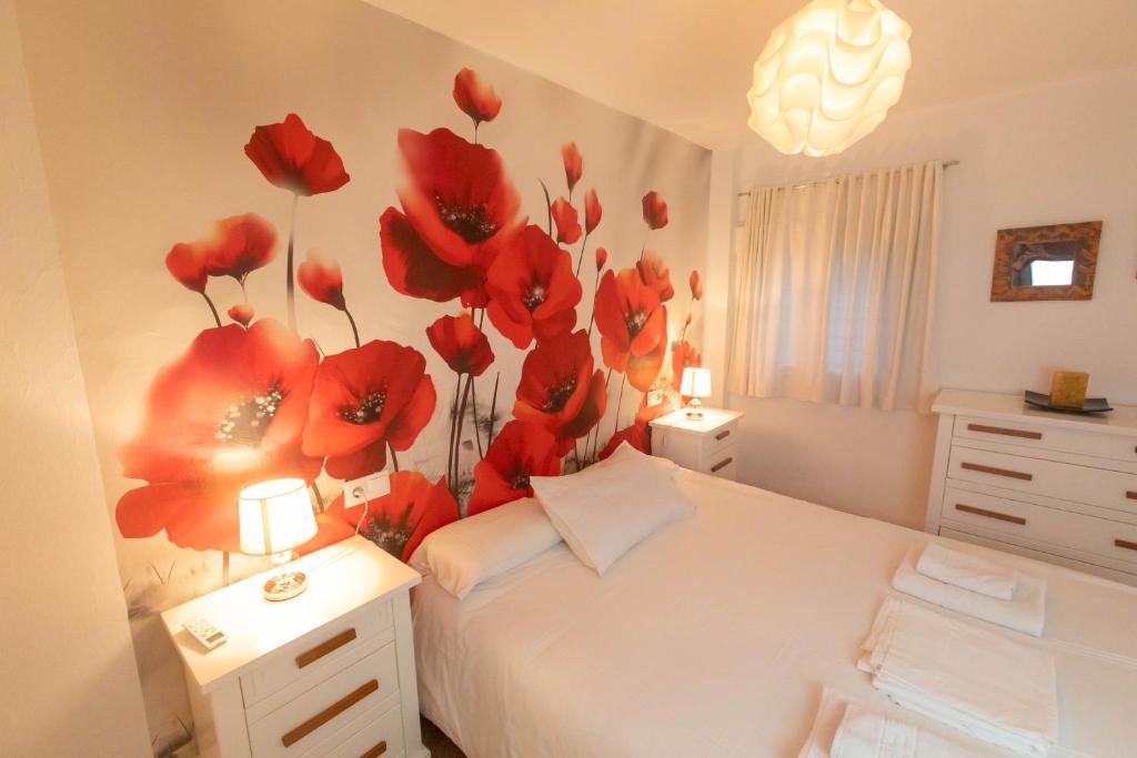 卡索拉Casa de las Flores Cazorla的卧室配有一张挂着红色鲜花的床。