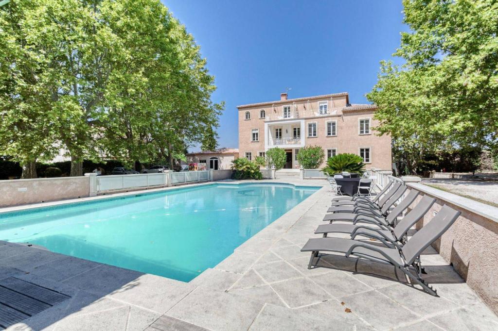 Gignac-la-NertheDOMAINE DE LA NERTHE- HOTEL PROVENCE MEDITERRANEE的一座带躺椅的游泳池和一座建筑