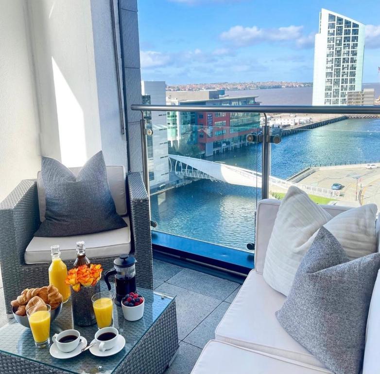 利物浦NOVU Apartments Liverpool Waterfront的阳台配有带饮品的桌子,享有水景