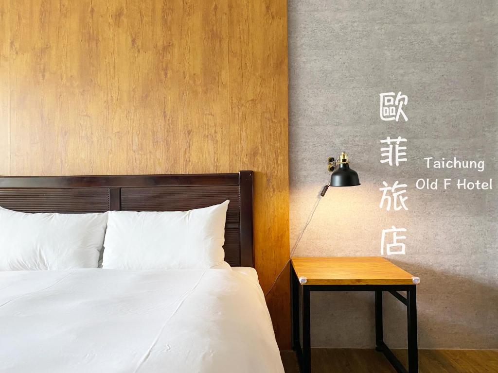 台中市台中欧菲旅店的一间卧室配有一张床和一张带台灯的桌子