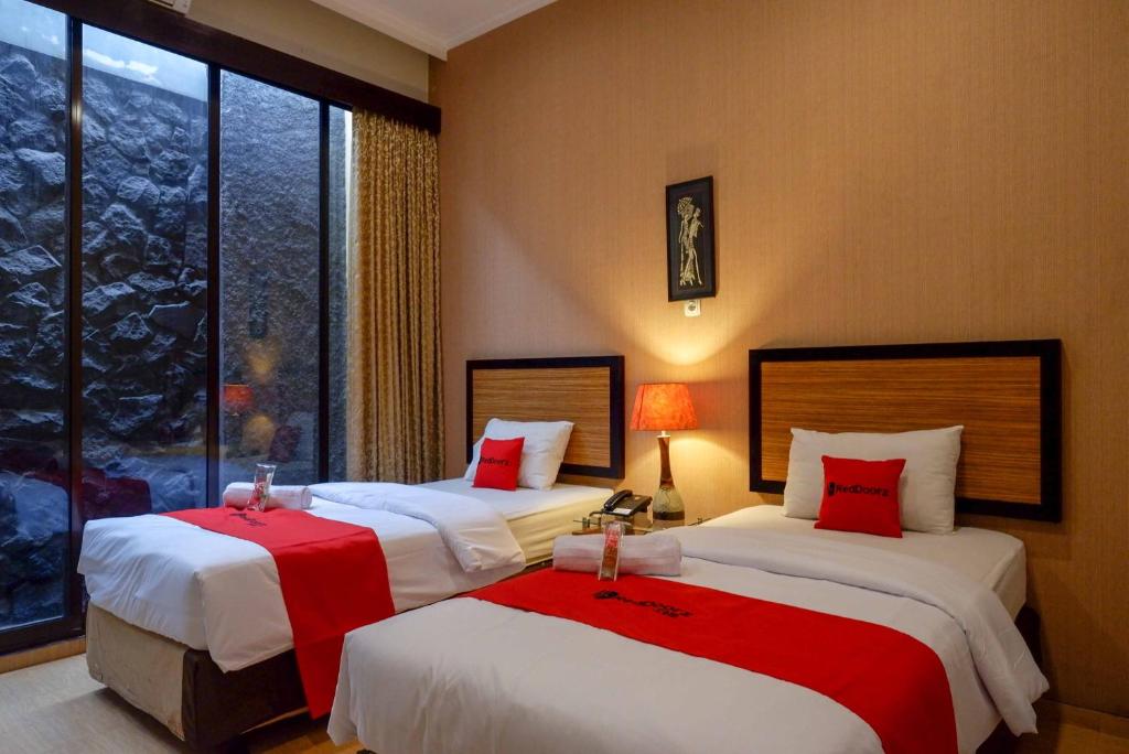 DemanganRedDoorz Plus near Amplaz Yogyakarta的酒店客房 - 带两张带红色枕头的床