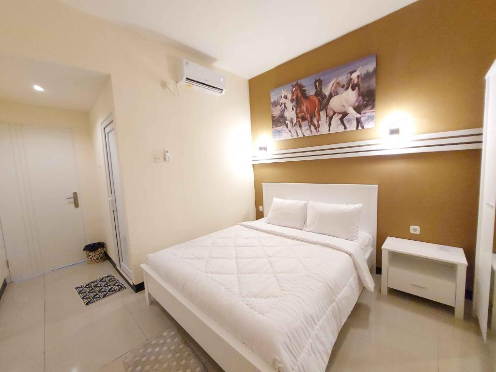 三宝垄Rons City Hotel near Simpang Lima Semarang Mitra RedDoorz的卧室配有白色的床和墙上的绘画作品