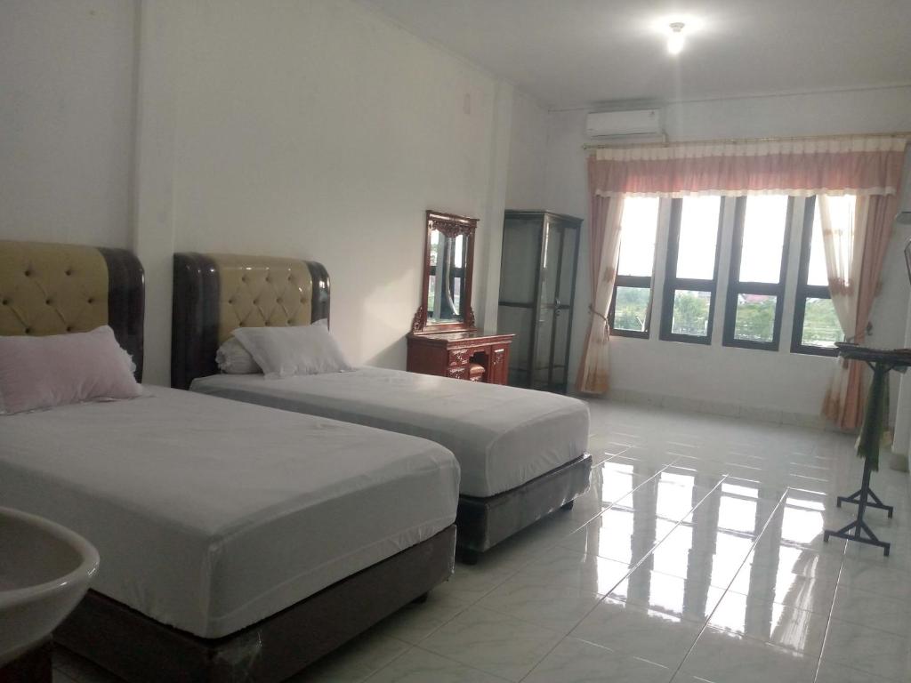 Sua DokataHomestay Hilal Meulaboh Syariah RedPartner的一间卧室设有两张床和一个水槽,窗户