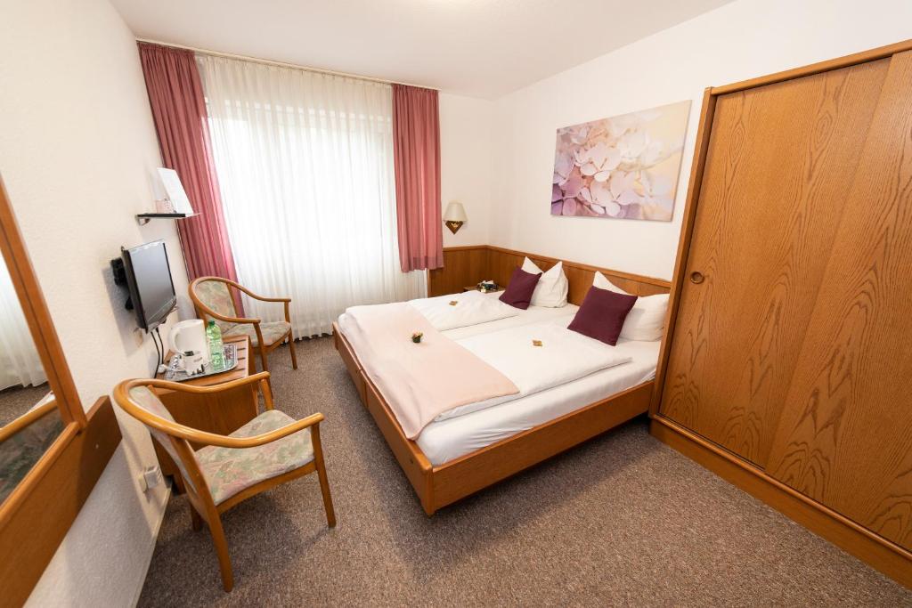 埃森Hotel am Schlosspark Essen的配有一张床和一把椅子的酒店客房