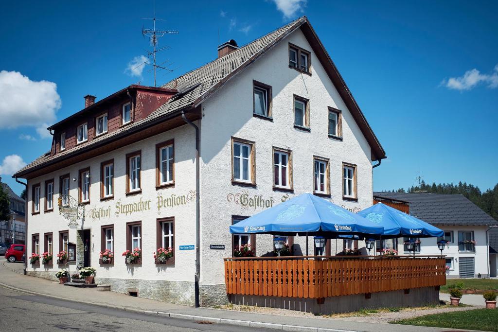 FriedenweilerGasthof & Pension Steppacher的前面有蓝色伞的白色建筑