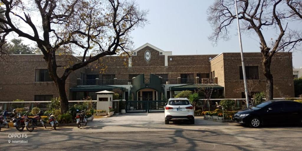 伊斯兰堡Welcome Hotel Islamabad的停在大楼前停车场的白色汽车