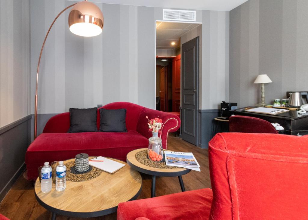 里昂亚历山德拉酒店的客厅配有红色的沙发和桌子