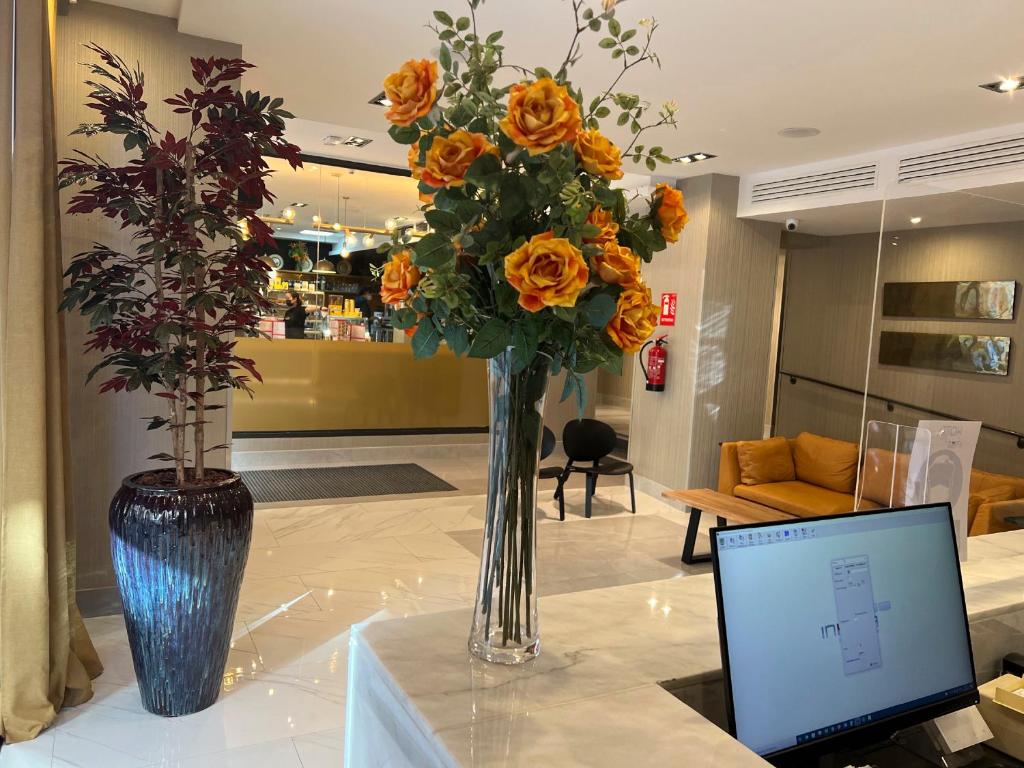 马德里格兰大街阿文尼达酒店的花瓶,花朵橙色,桌子上放着笔记本电脑
