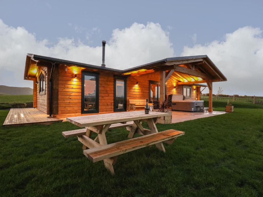 马汉莱斯Bacheiddon Log Cabin的小木屋前方设有野餐桌
