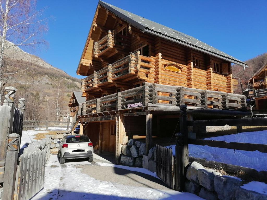 阿洛斯Chalet Les Pins Blancs的雪地里的小木屋,外面有停车位