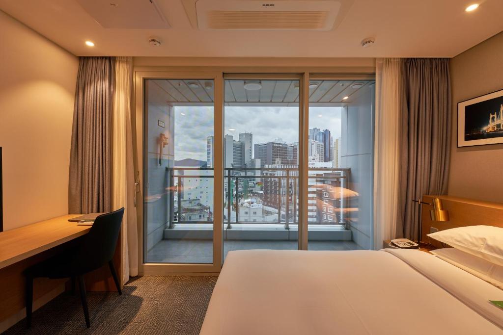 釜山Lavi De Atlan Hotel 2的配有一张床、一张书桌和一扇窗户的酒店客房