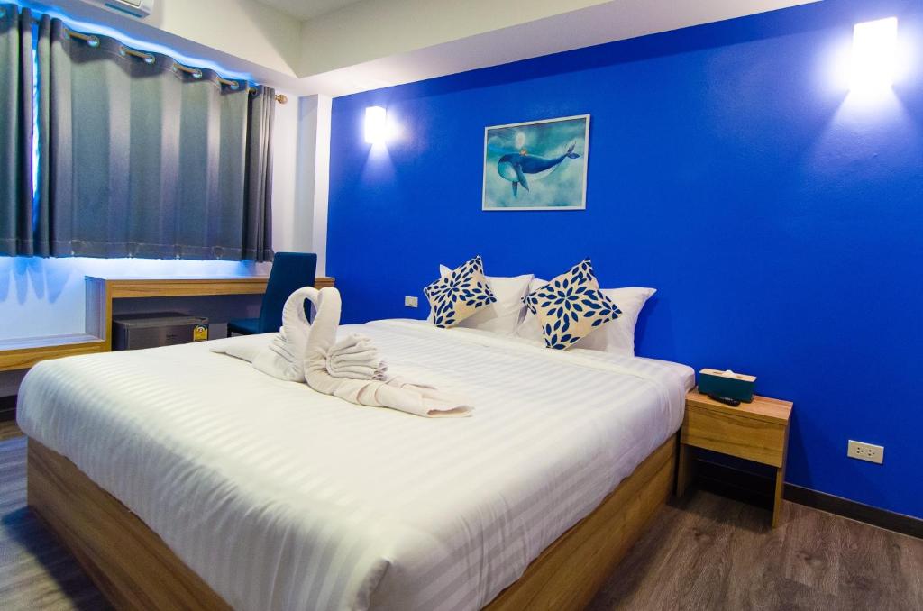 Ban Nong SrahBleu Marine Sattahip Hotel的一间卧室设有一张蓝色墙壁的大床