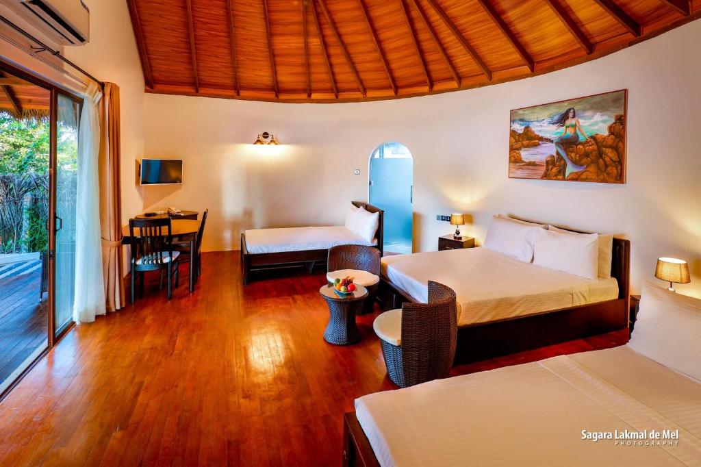 卡尔皮蒂耶The Blue Lagoon Resort Kalpitiya的酒店客房带两张床和一张桌子以及椅子。