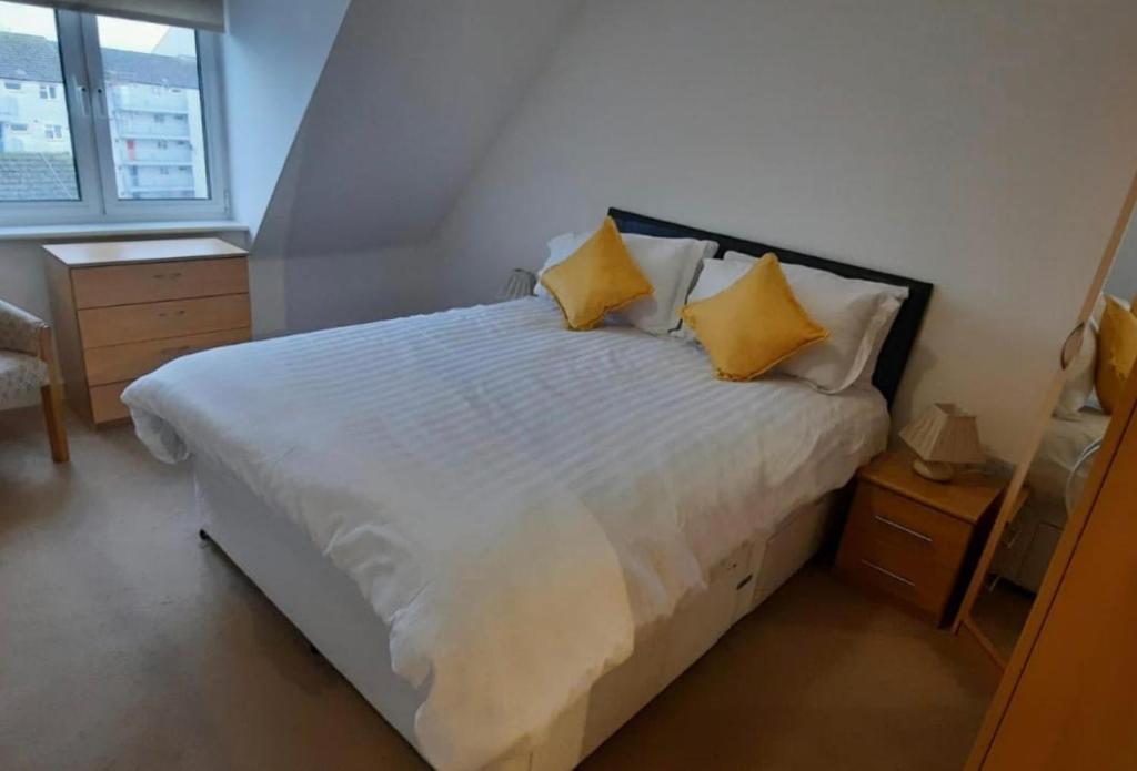 北安普敦Apartment D505的一间卧室配有白色床和黄色枕头