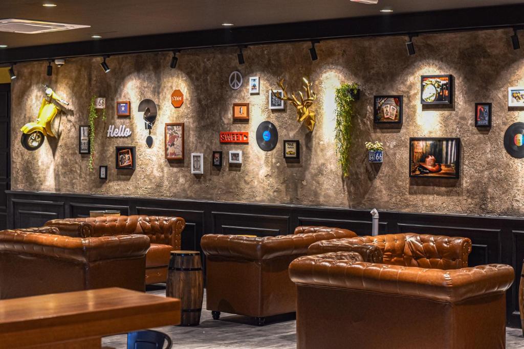 怡保Zone Hotel Ipoh的酒吧配有皮椅和墙上的照片