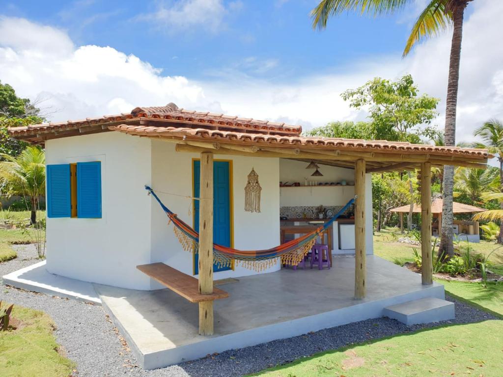 库穆鲁沙蒂巴Canto do Mar - Chalés com vista pro Mar - Cumuruxatiba的白色的小房子,设有门廊和吊床
