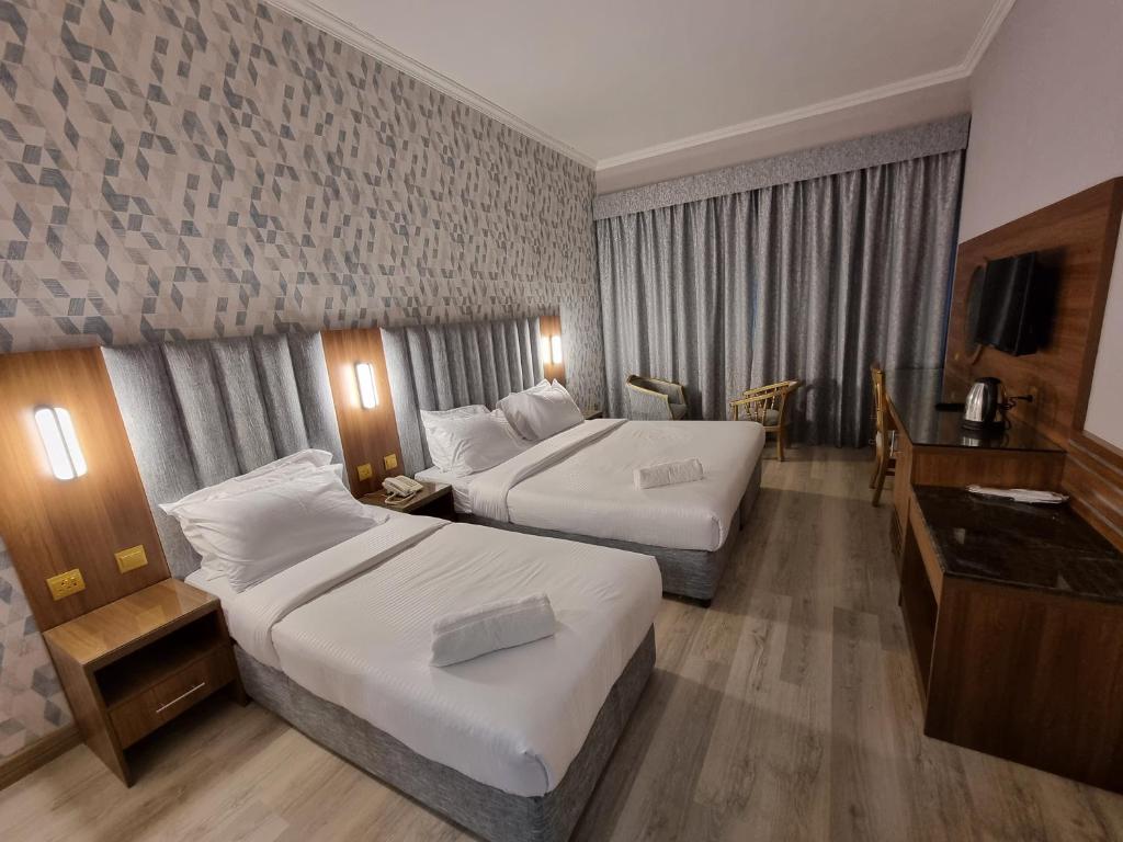 迪拜Vista Square Hotel的酒店客房配有两张床和一张书桌