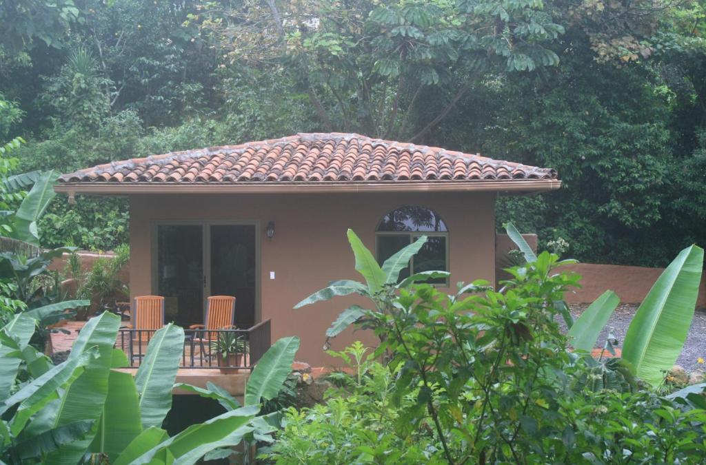 下博克特The Casita at The Boquete Hacienda的花园中带瓷砖屋顶的小房子