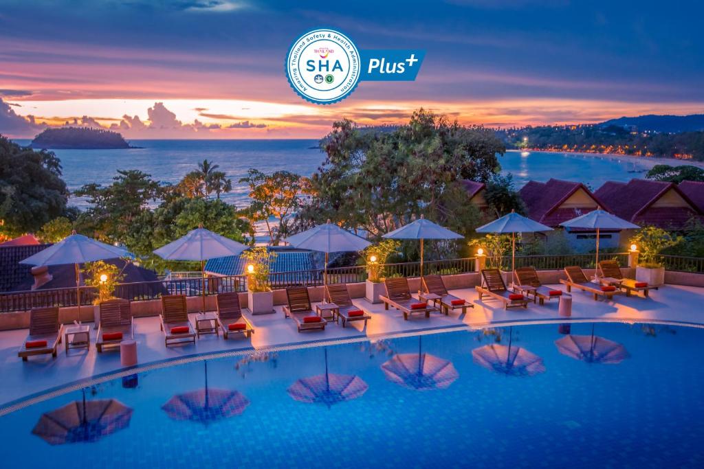 卡塔海滩Chanalai Garden Resort, Kata Beach的夜间带椅子和遮阳伞的酒店游泳池