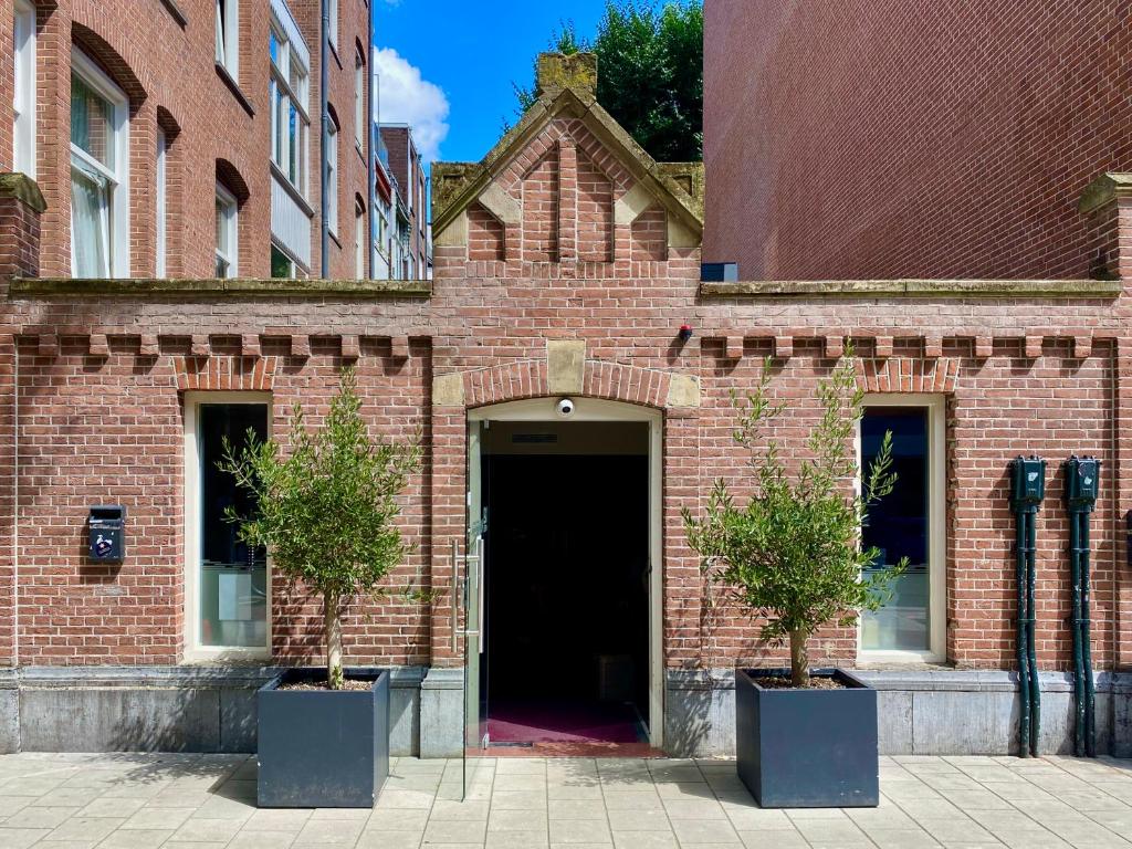 阿姆斯特丹Hotel Van Gogh的砖砌的建筑,有门,两棵树在盆里