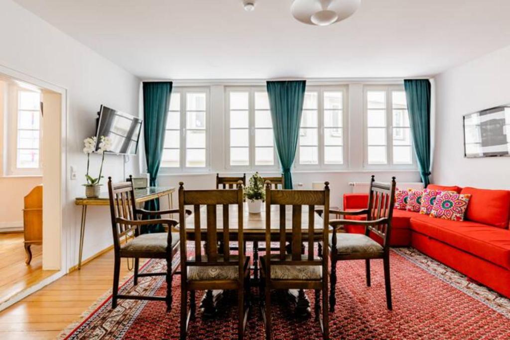 蒂宾根Apartment Zentral的一间带桌子和红色沙发的用餐室