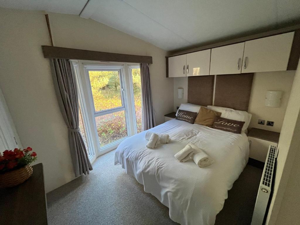 莫珀斯Hazel Oaks, Beautiful Lodge with Hot Tub - Sleeps 6 - Felmoor Park的一间卧室配有带毛巾的床