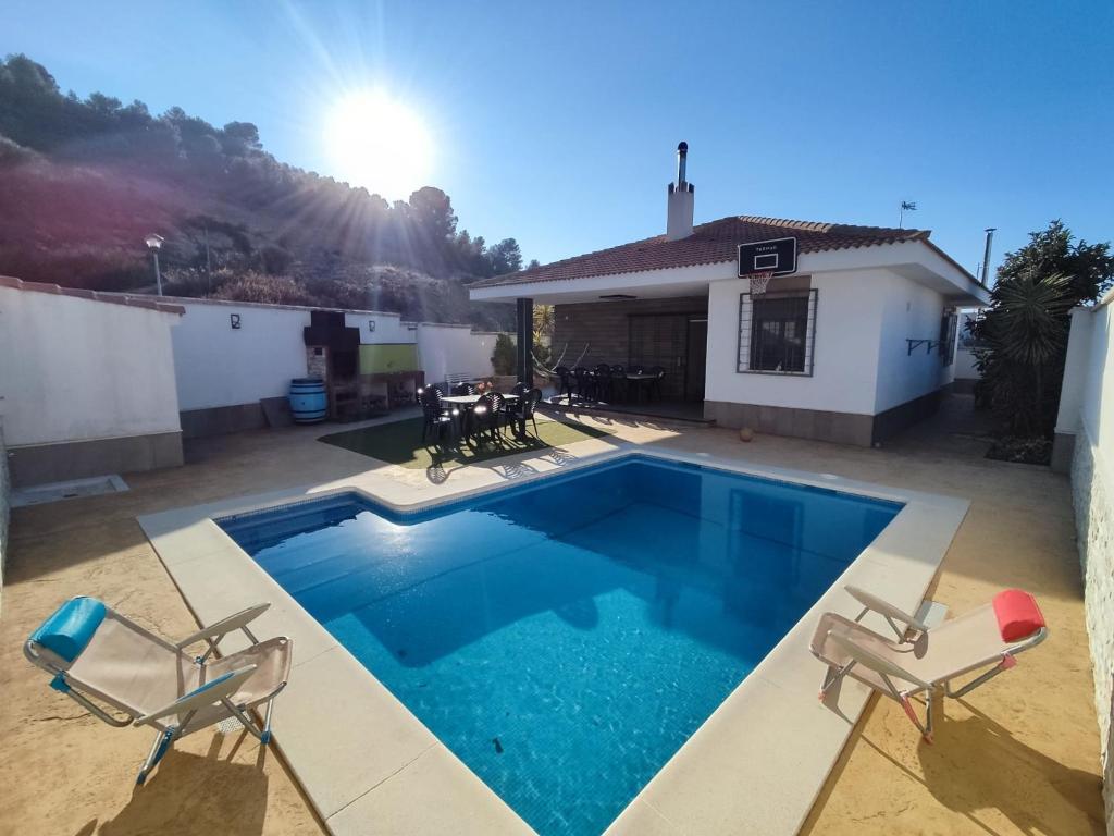 Los VillaresVilla Campoamor的一个带两把椅子的游泳池以及一座房子