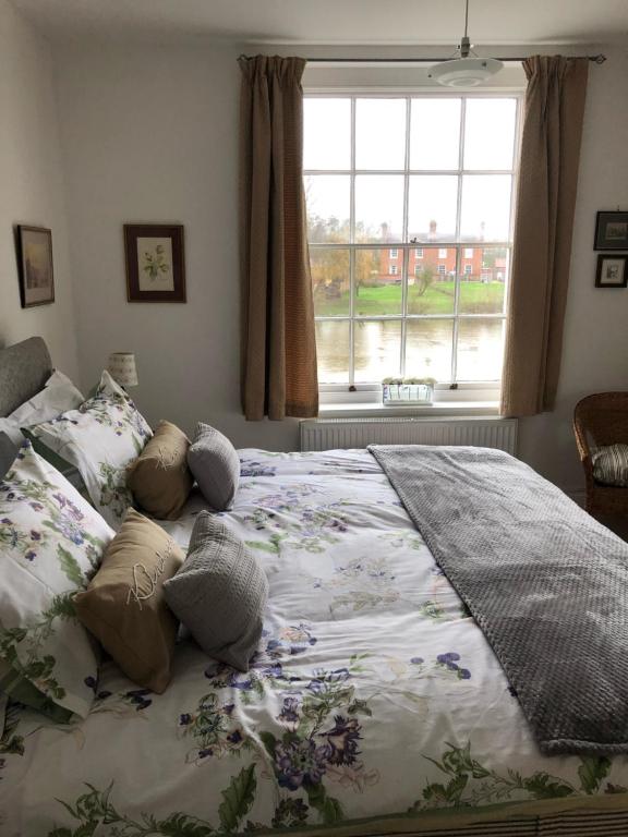 塞文河畔厄普顿Beautiful riverfront cosy one bedroom apartment的卧室配有带枕头的大床和窗户。