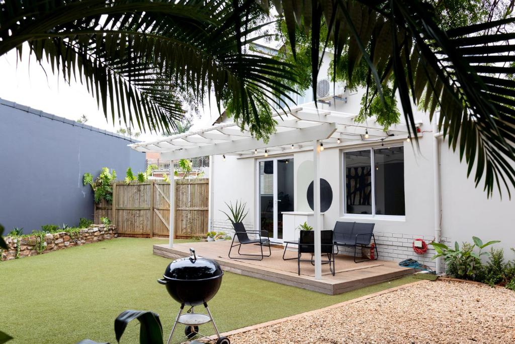 德班Peaceful Modern Home with Private Garden in Durban North的一个带烧烤炉和房子的后院