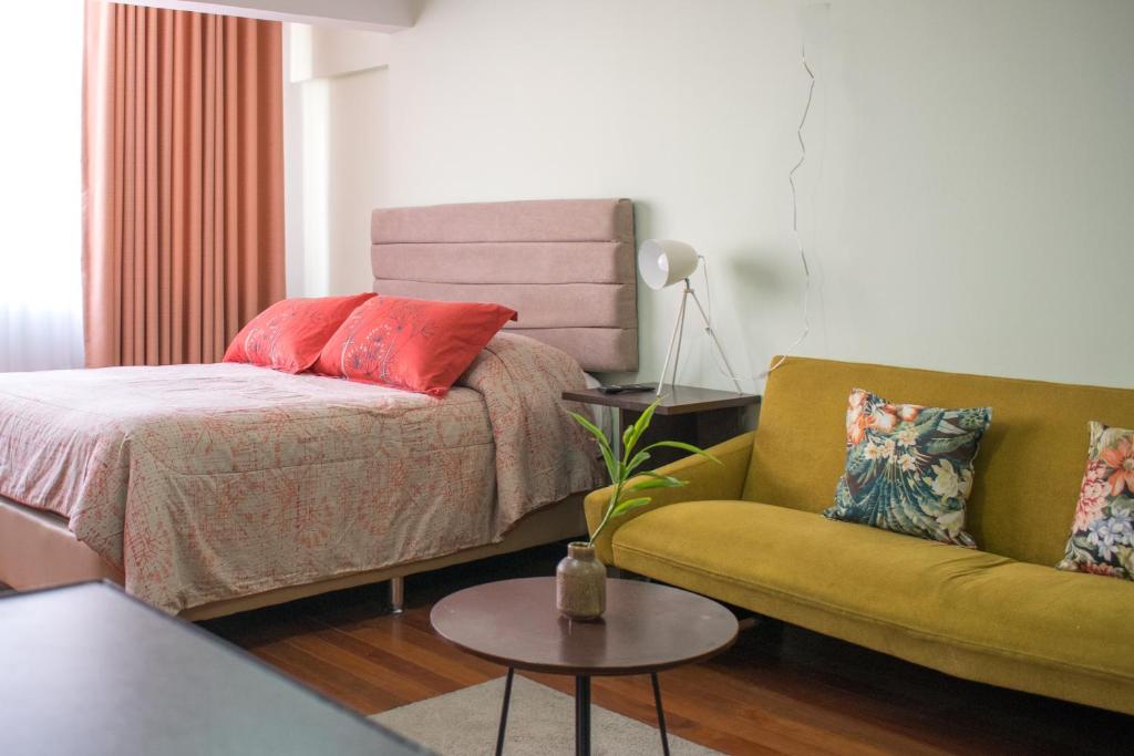 拉巴斯Skyline的一间卧室配有一张床、一张沙发和一张桌子