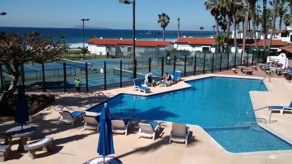 罗萨里托Great Beach Swiming Pools Tennis Courts Condo in La Paloma Rosarito Beach的一个带椅子和遮阳伞的游泳池