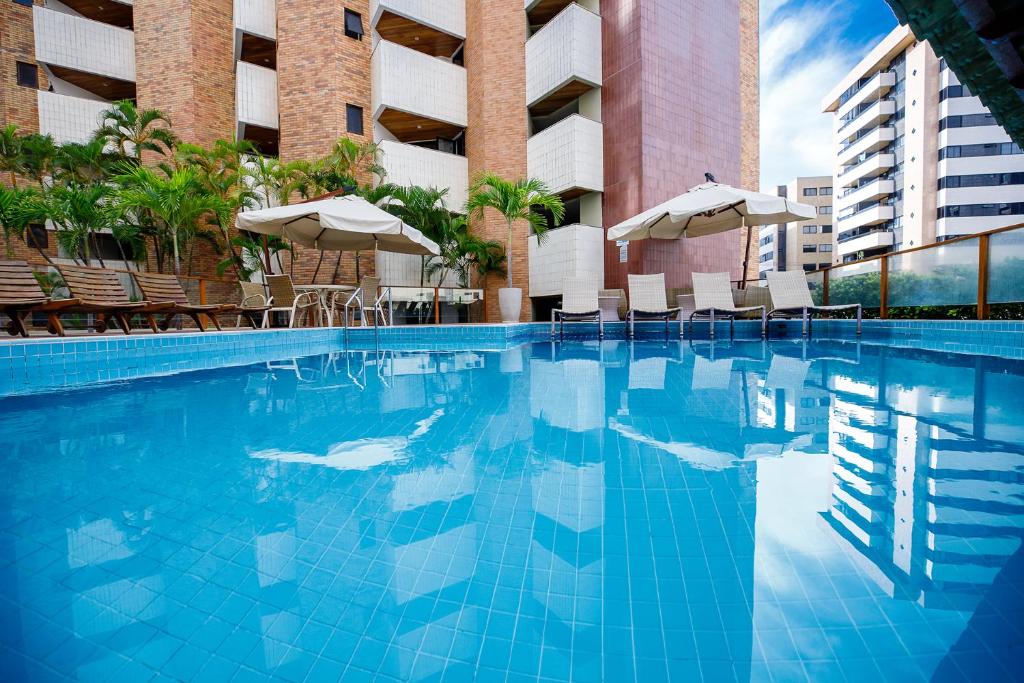 马塞约圣马力诺套房酒店的一座带椅子和遮阳伞的游泳池位于一座建筑旁边