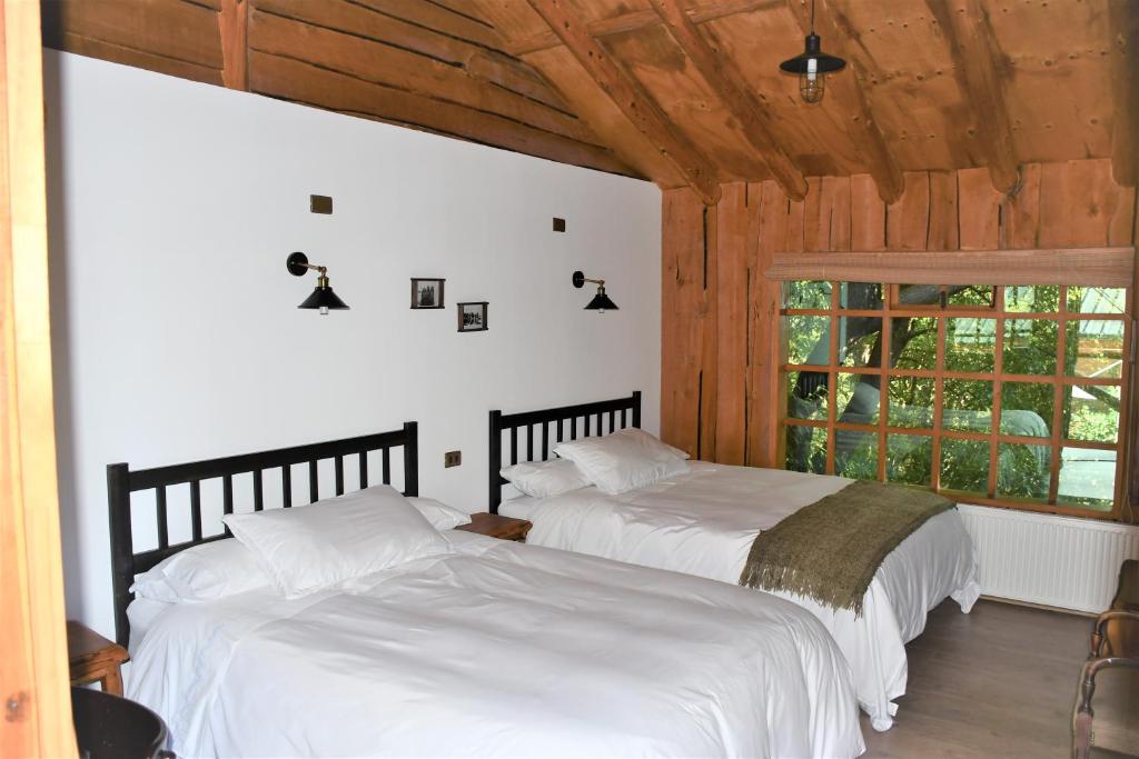富塔莱乌富Hotel El Barranco的配有白色床单和窗户的客房内的两张床