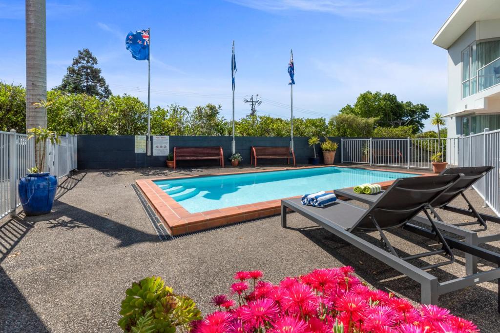 奥克兰亚里士多德北岸酒店的一个带躺椅、椅子和鲜花的游泳池