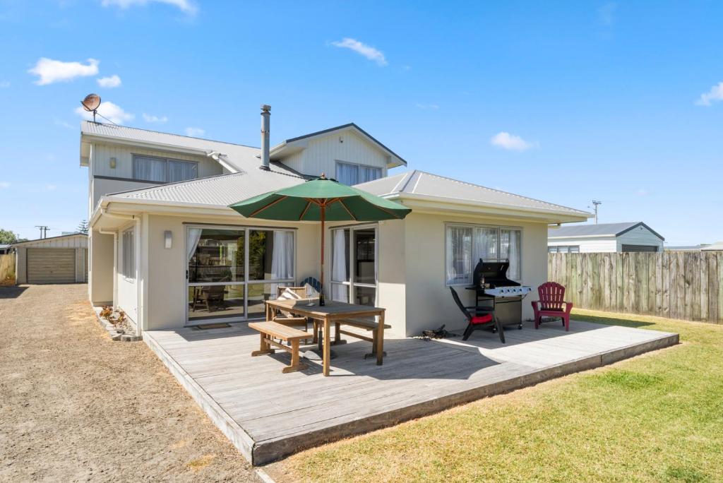 Oroua DownsHunia Haven - Himatangi Beach Holiday Home的房屋设有带桌子和遮阳伞的庭院