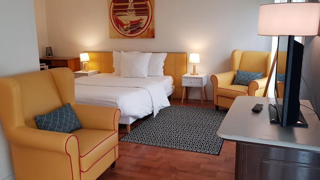 奥尔日河畔布雷蒂尼Résidence Carouge Appart Hôtel的酒店客房,配有一张床和两把椅子