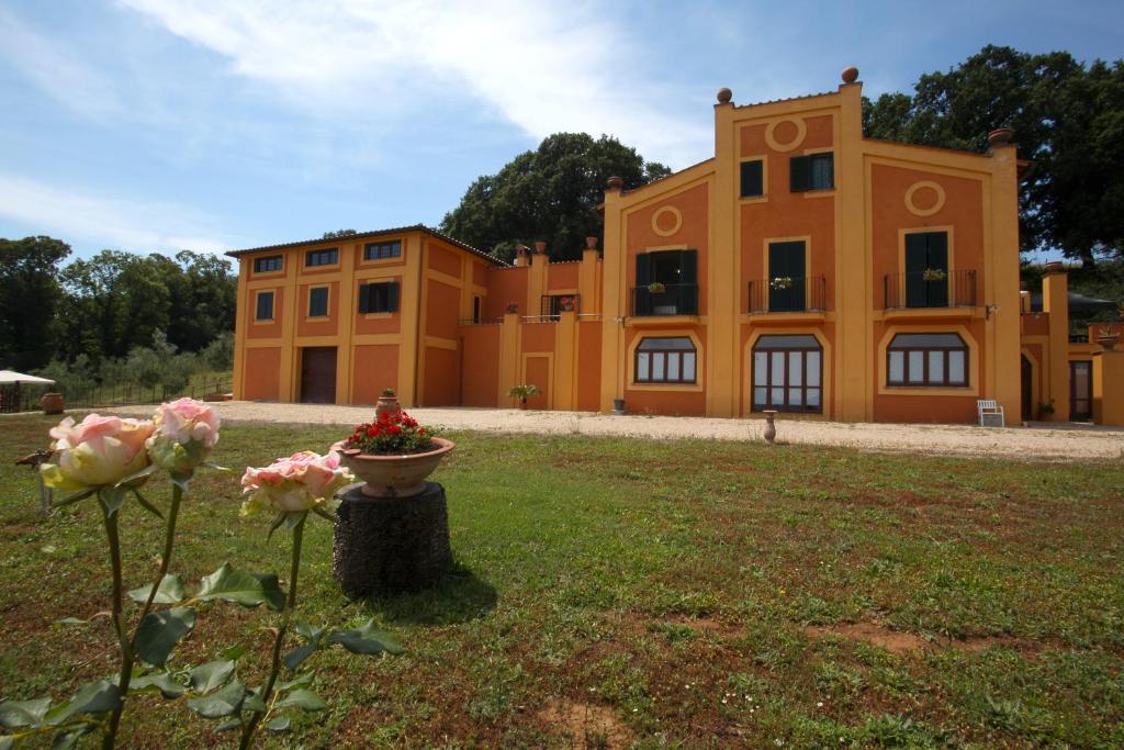 布拉恰诺拉吉斯孟达农家乐的一座大橙色的建筑,在院子里种着鲜花