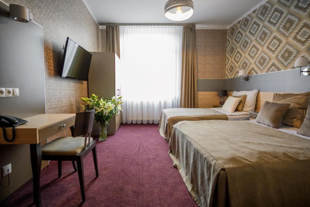 克拉科夫卡齐米日酒店的酒店客房设有两张床、一张书桌和一个窗户。